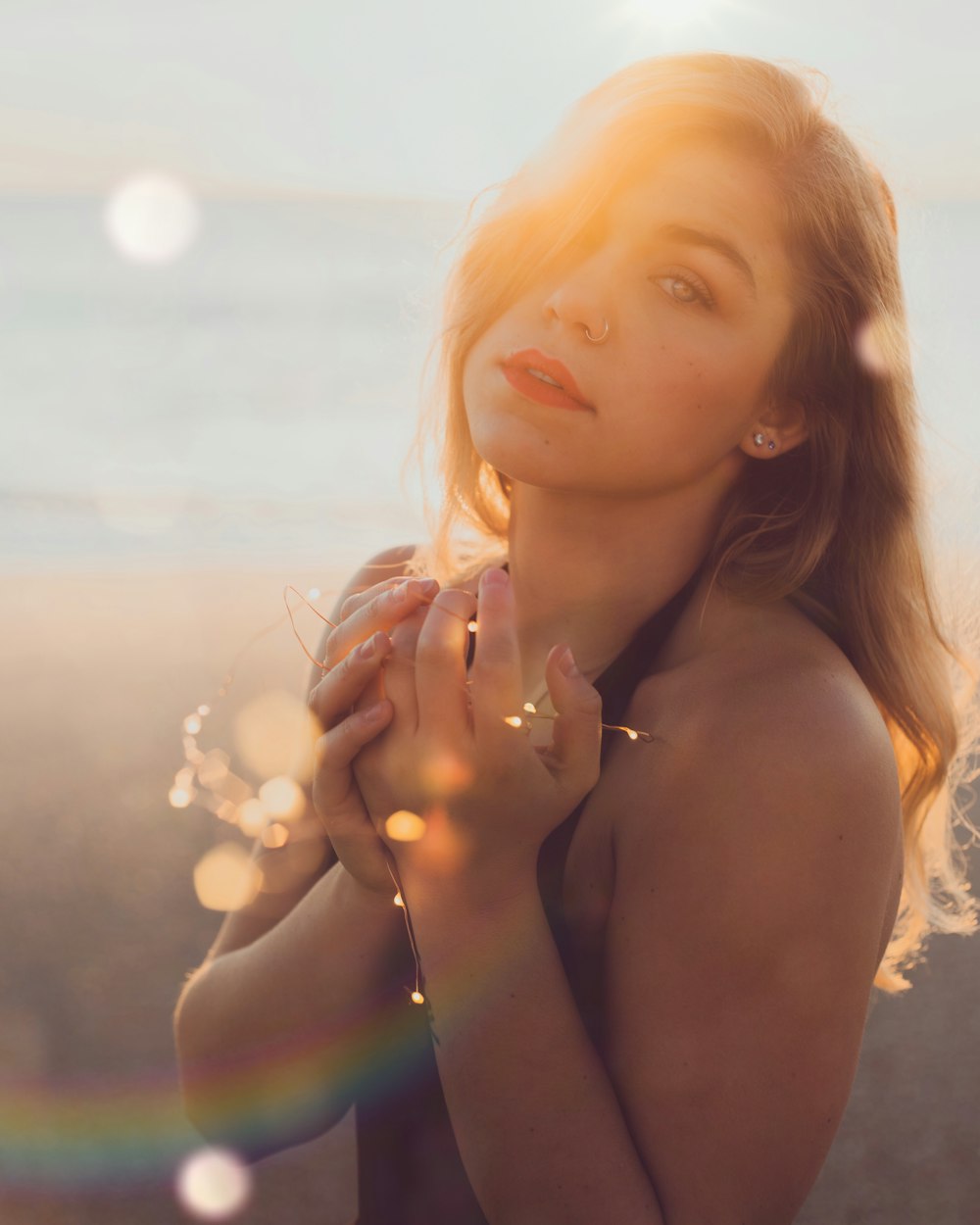 woman in purple tank top holding yellow string lights during sunset
