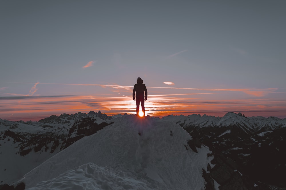 man in black jacket standing on white snow covered ground during daytime