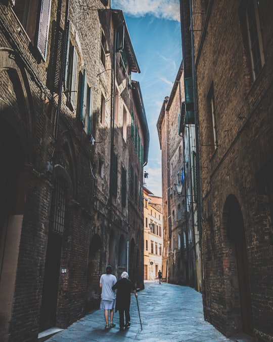 people walking on street between buildings during daytime in Siena Italy