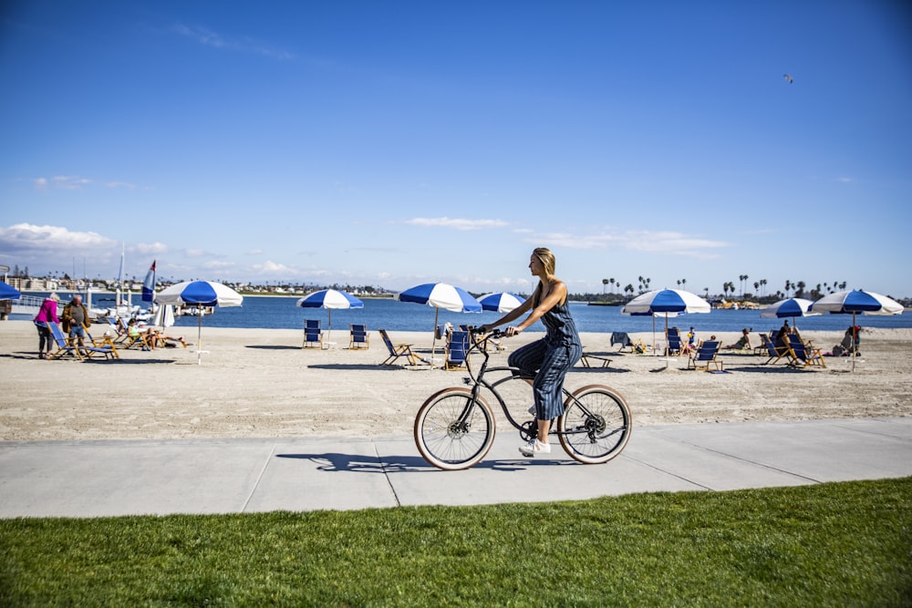 woman in black tank top riding on bicycle on gray concrete road during daytime