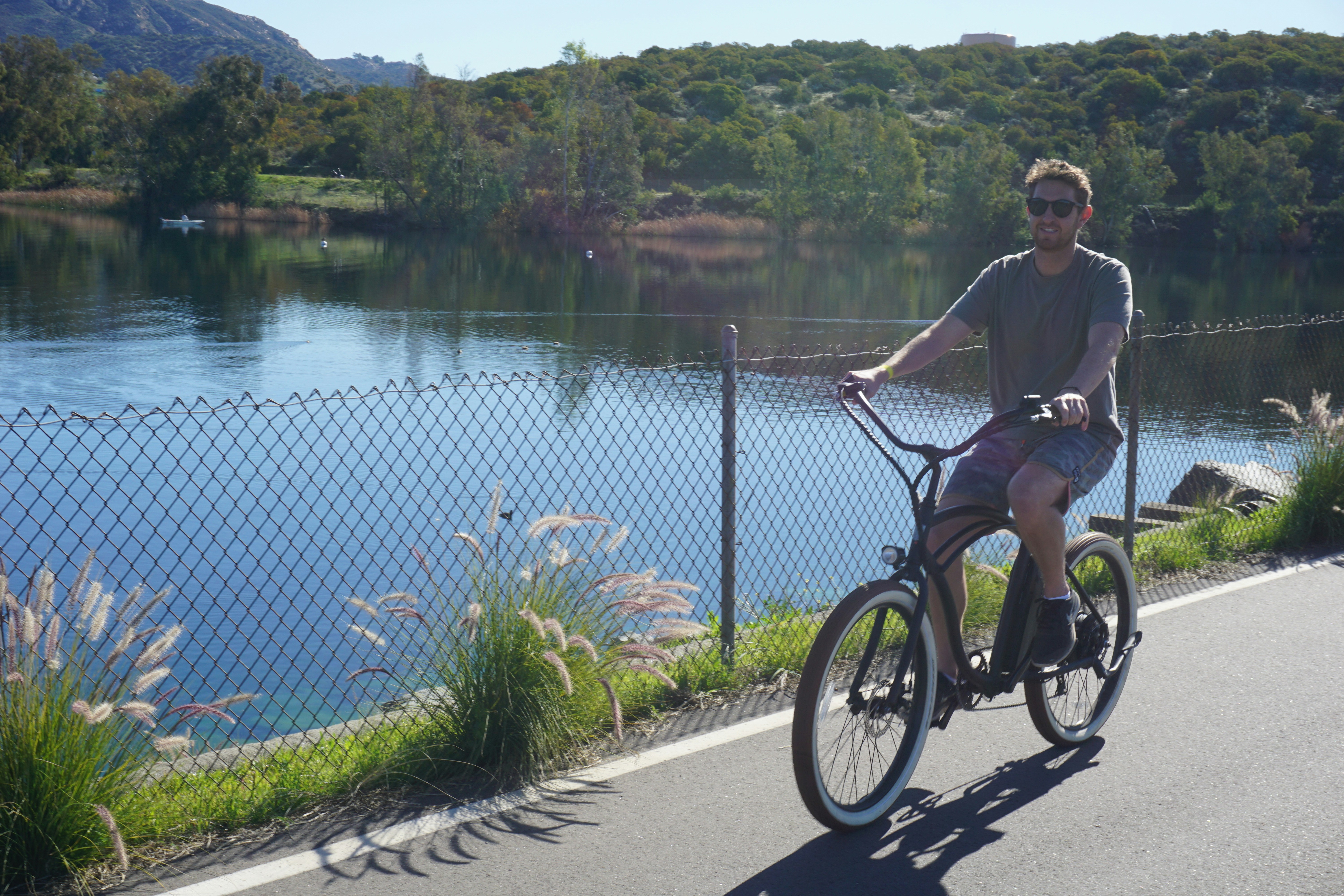 man in black jacket riding on bicycle near body of water during daytime