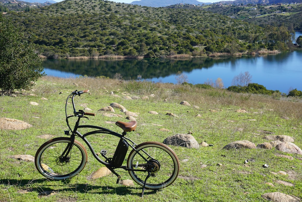 black commuter bike on white rocks near lake during daytime