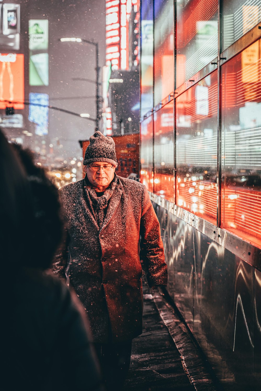 a man walking down a sidewalk in the snow