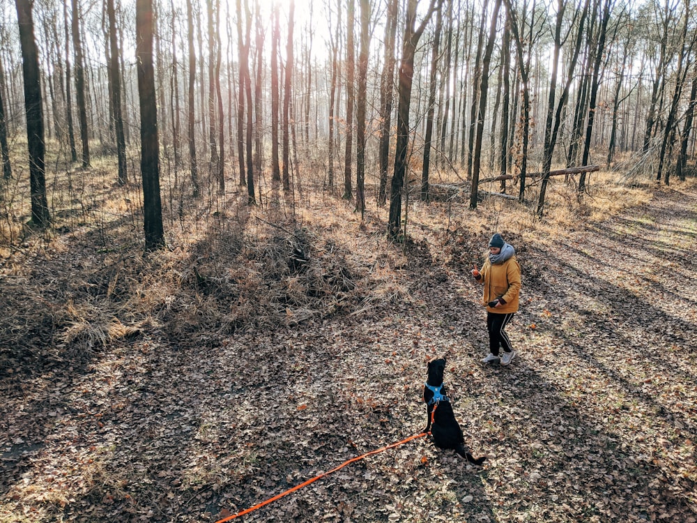 woman in yellow jacket walking on dirt road between trees during daytime