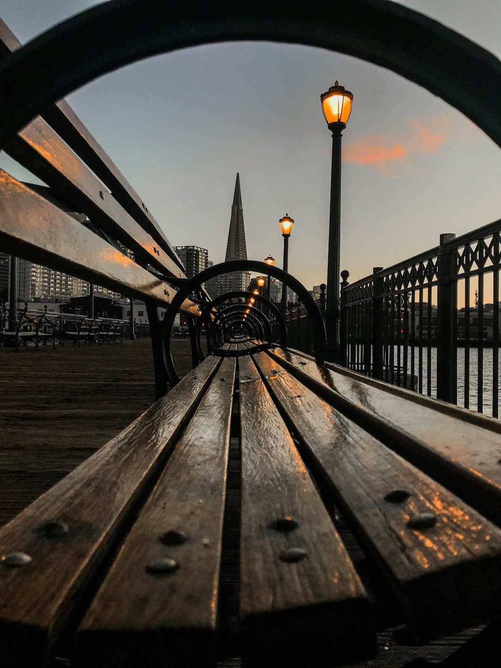 brown wooden bench near black metal railings during daytime