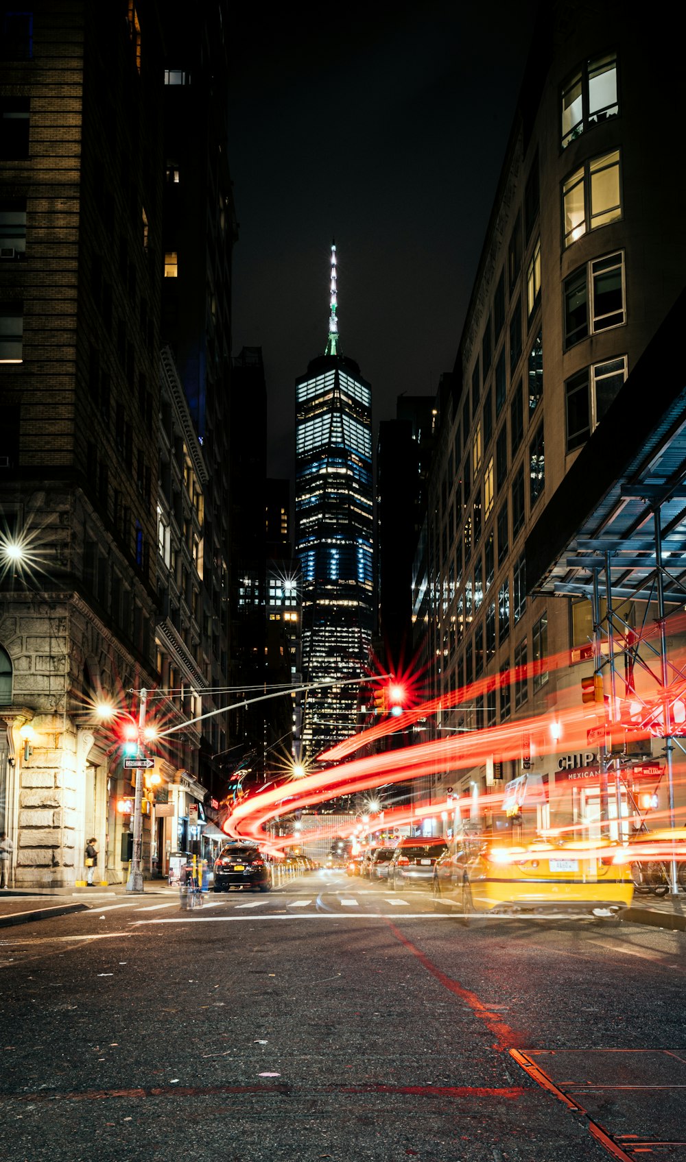 cars on road between high rise buildings during night time