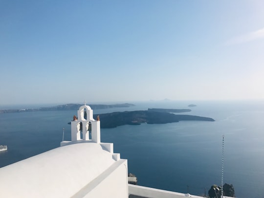 white concrete building near body of water during daytime in Santorini Greece