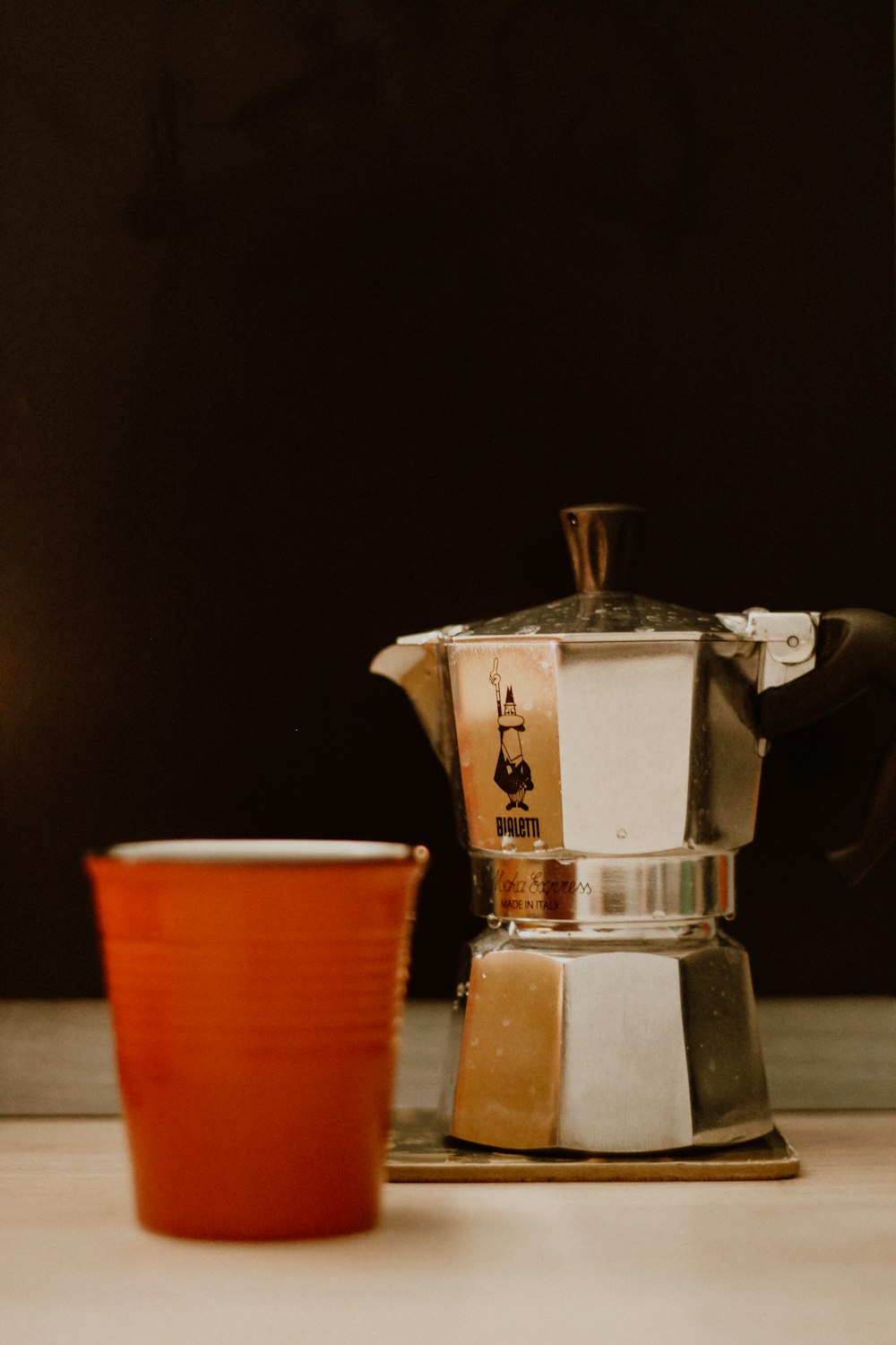 a coffee pot sitting on top of a table next to a cup