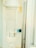 A close-up view of a medical intravenous (IV) drip chamber, partially filled with a clear liquid and several air bubbles. The background appears to be a sterile hospital or clinical setting, characterized by neutral and light-colored surfaces.