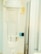 A close-up view of a medical intravenous (IV) drip chamber, partially filled with a clear liquid and several air bubbles. The background appears to be a sterile hospital or clinical setting, characterized by neutral and light-colored surfaces.