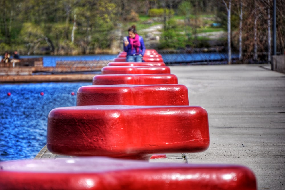 person in blue jacket sitting on red plastic chair