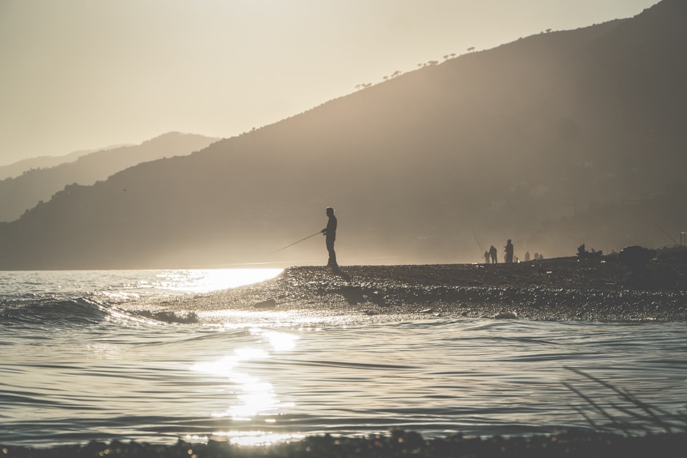 silhouette of person standing on beach during sunset