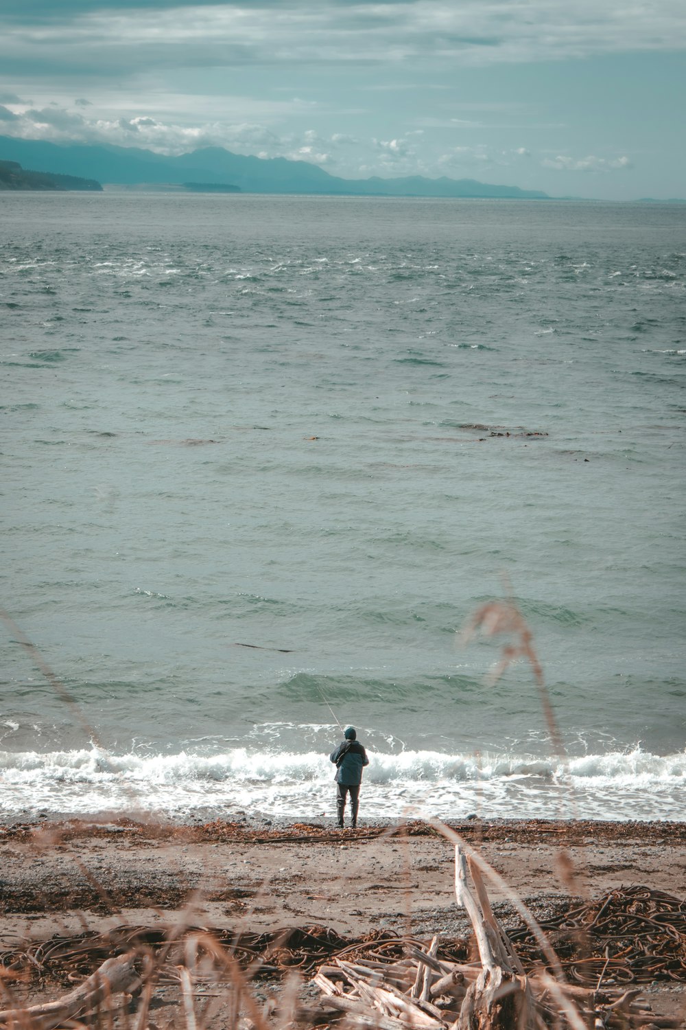 man in black shirt and black shorts standing on beach shore during daytime