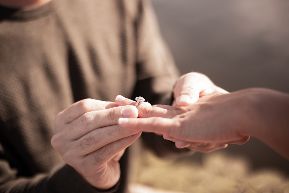 person holding silver diamond ring