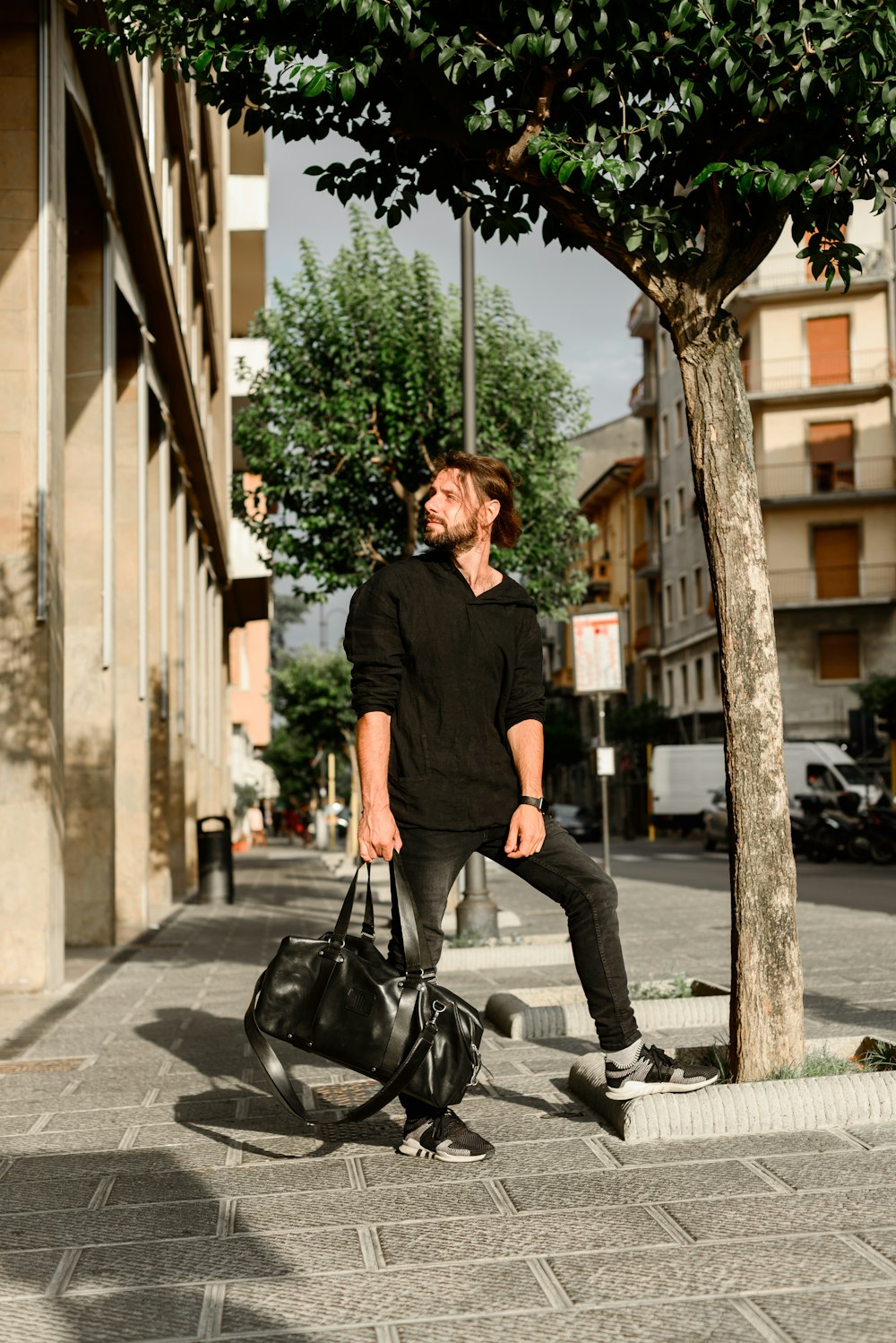 woman in black long sleeve shirt and black pants sitting on sidewalk during daytime