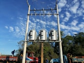 Technician performing maintenance on a large electrical transformer outdoors.
