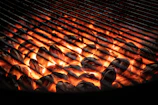 A sleek stainless steel gas BBQ grill glowing under evening patio lights.