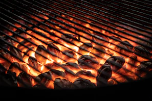 A sleek stainless steel gas BBQ grill glowing under evening patio lights.