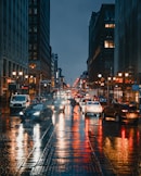 cars on road between high rise buildings during night time