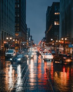 cars on road between high rise buildings during night time