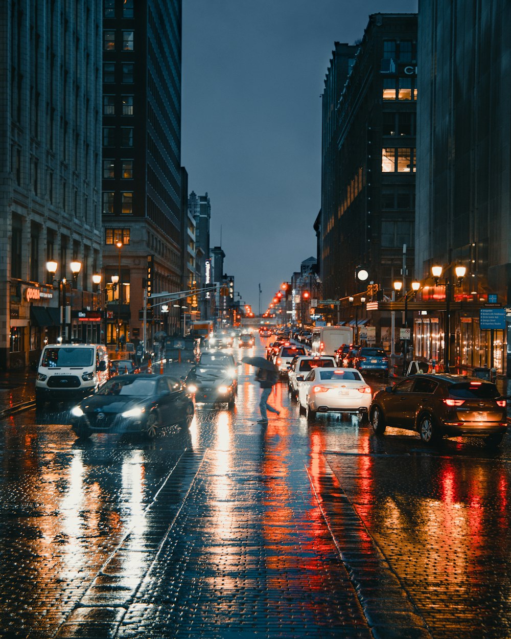 cars on road between high rise buildings during night time