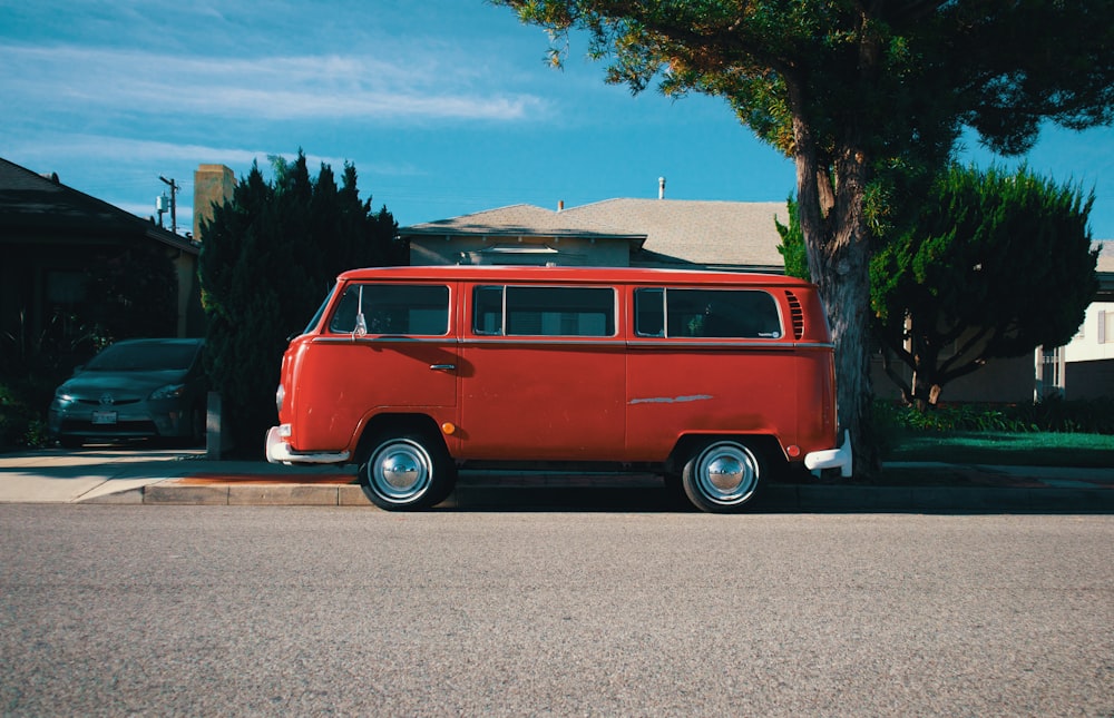 red and white volkswagen t-2 parked on gray concrete pavement during daytime