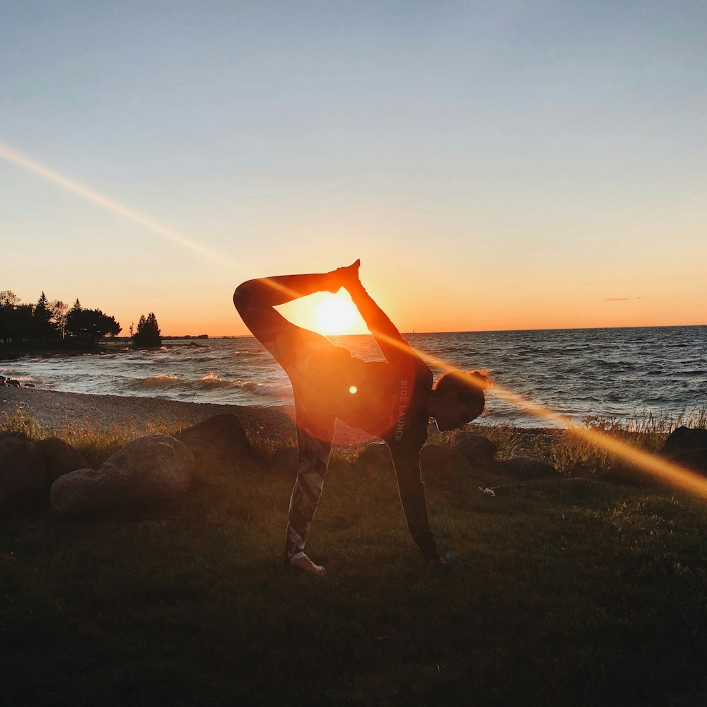 silhouette of person holding surfboard on beach during sunset