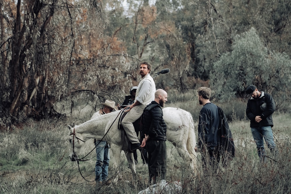 man in gray jacket and black pants sitting on white sheep