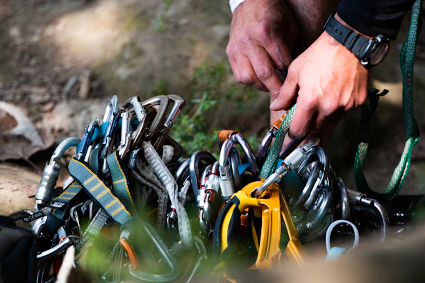 Close-up shot of climbing ropes and carabiners bundled neatly on a weathered wooden surface.