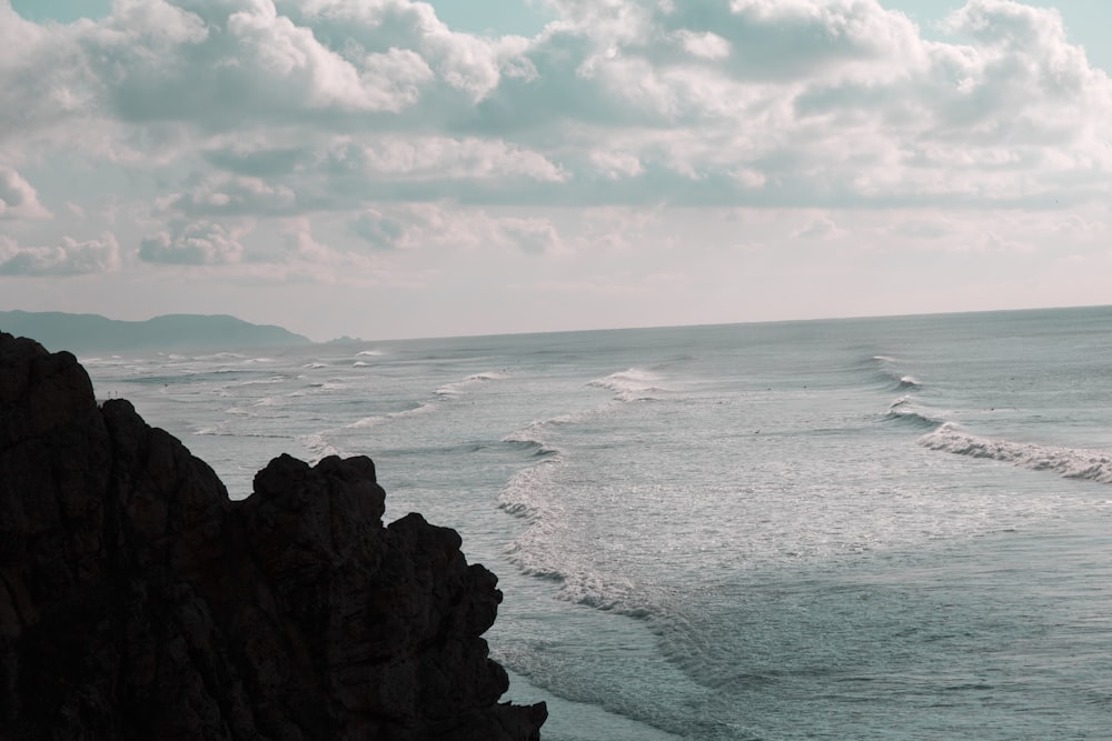 brown rock formation on sea under white clouds during daytime