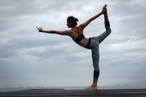 woman in black sports bra and blue leggings doing yoga during daytime