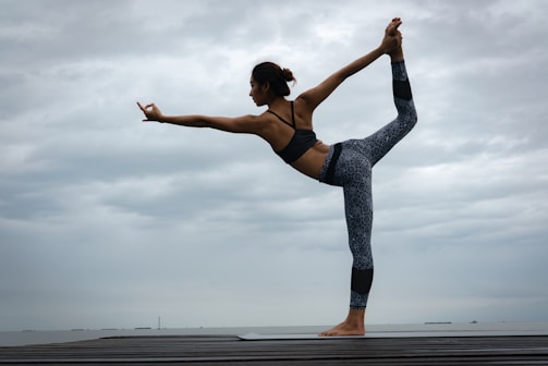woman in black sports bra and blue leggings doing yoga during daytime