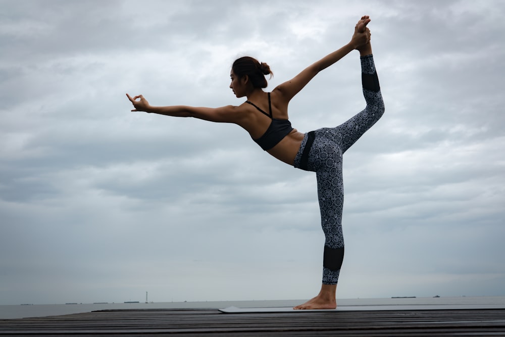 woman in black sports bra and blue leggings doing yoga during daytime