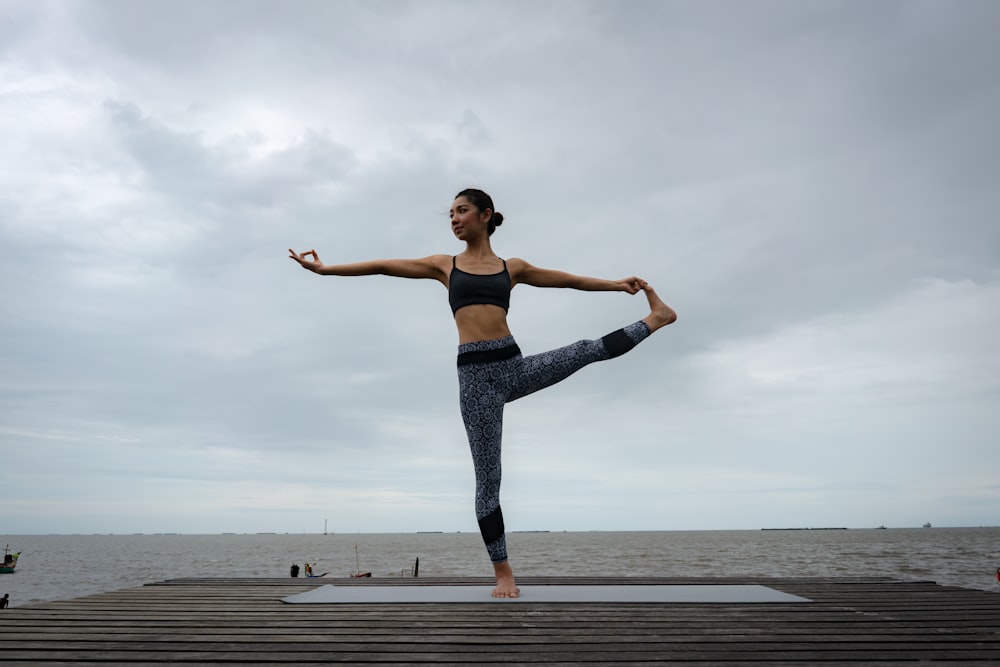 woman in blue denim jeans standing on brown wooden dock during daytime