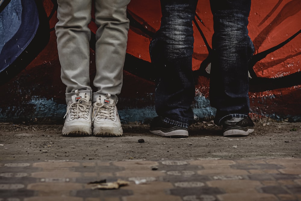 person in gray pants and white sneakers standing on brown wooden floor