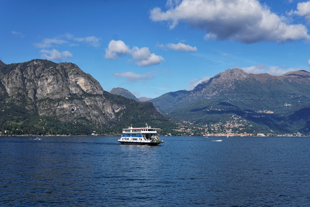 white boat on sea near mountain under blue sky during daytime