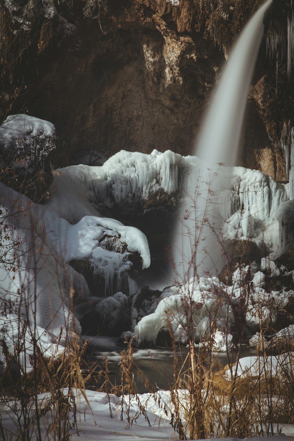 snow covered rocks on river during daytime