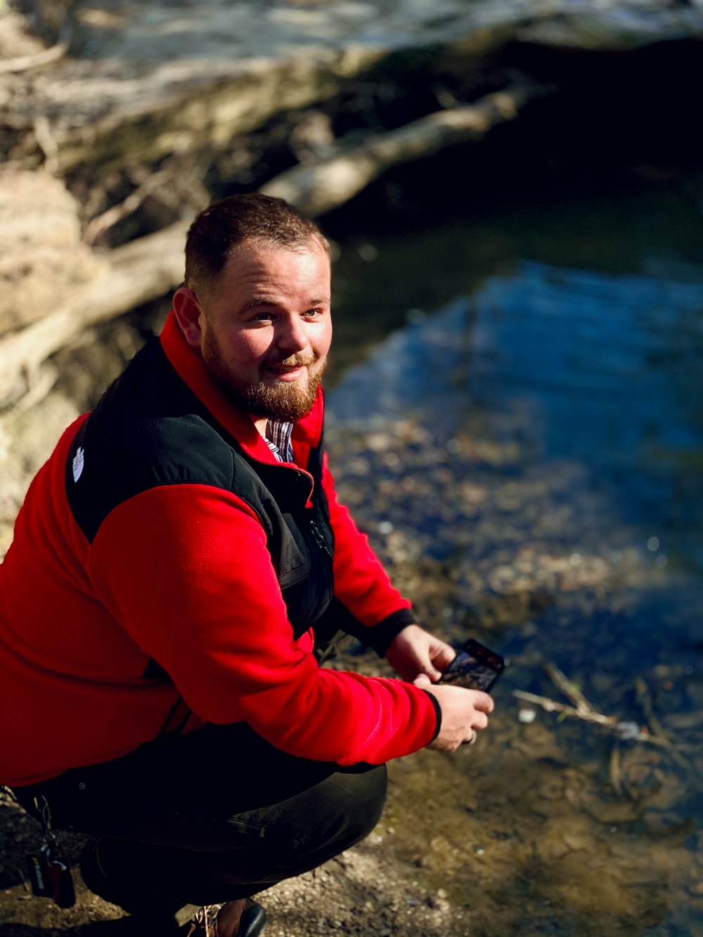 man in red and black long sleeve shirt sitting on rock