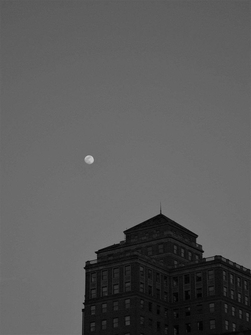 grayscale photo of full moon over building