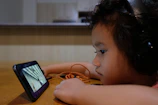 Parents and kids sharing headphones, immersed in music and stories on a smartphone.