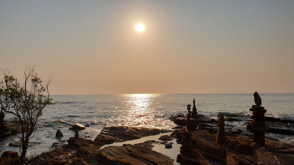 the sun is setting over the ocean and rocks