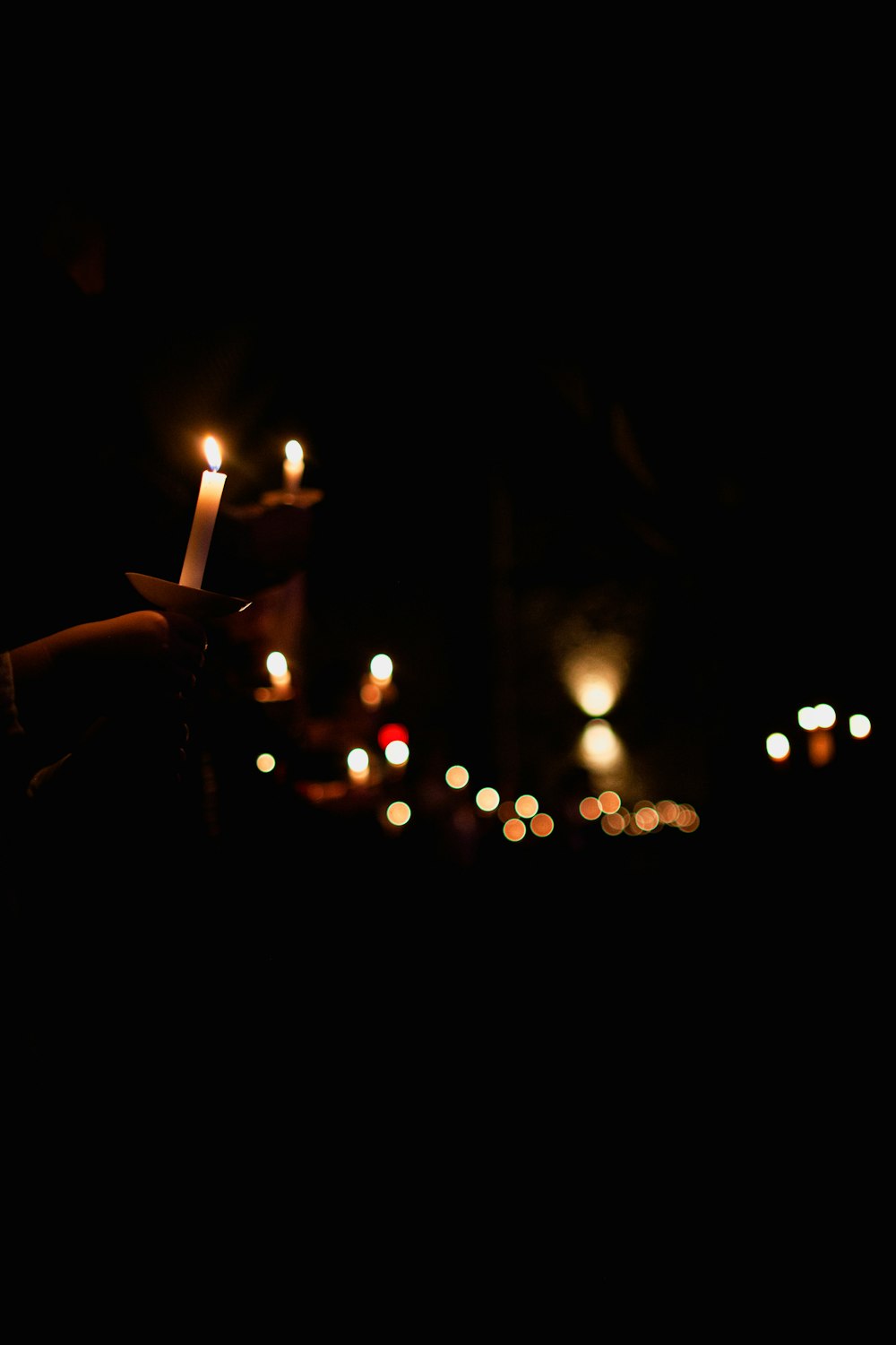 Person, die nachts eine brennende Kerze in der Hand hält