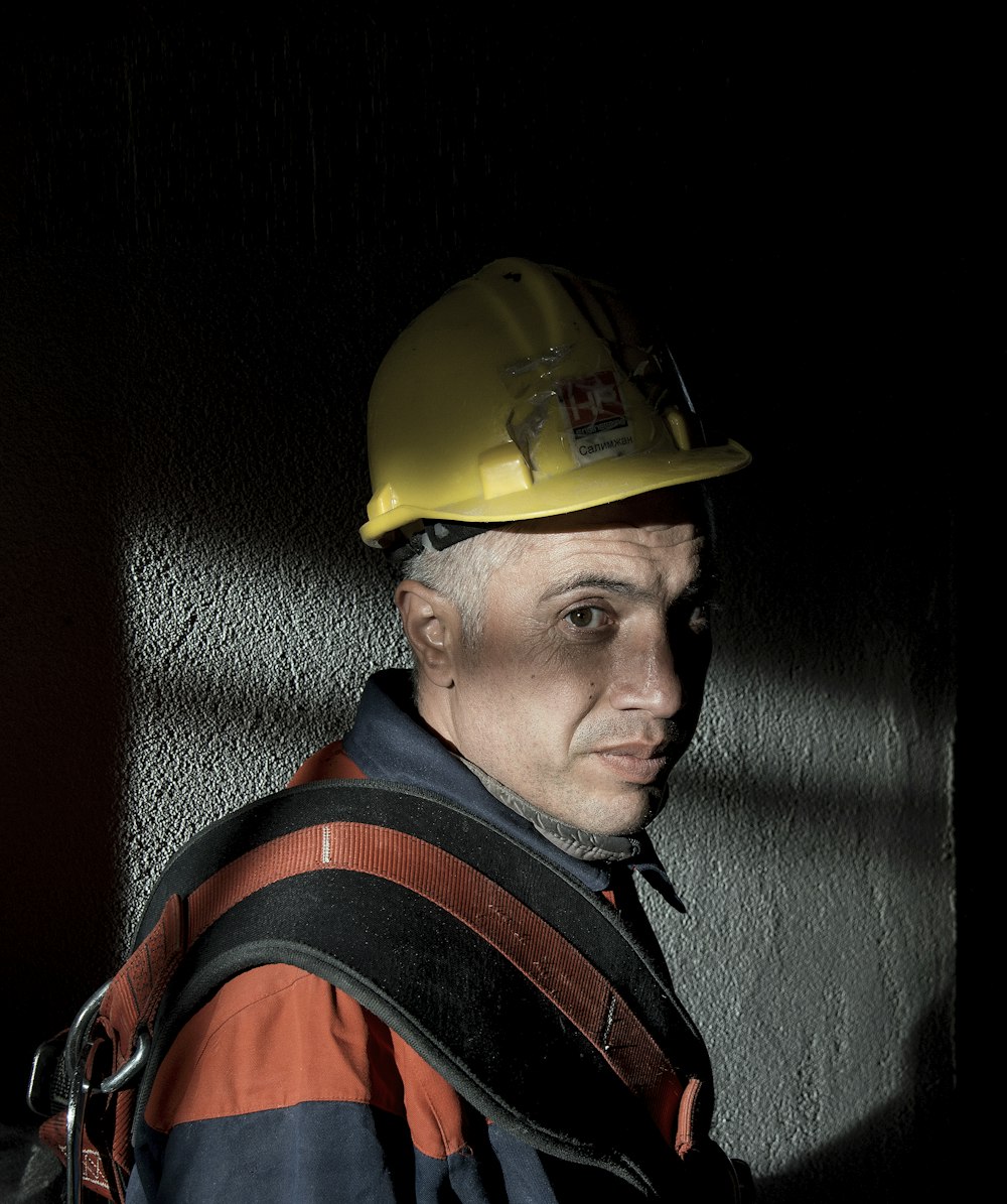 man in yellow hard hat and black and red jacket