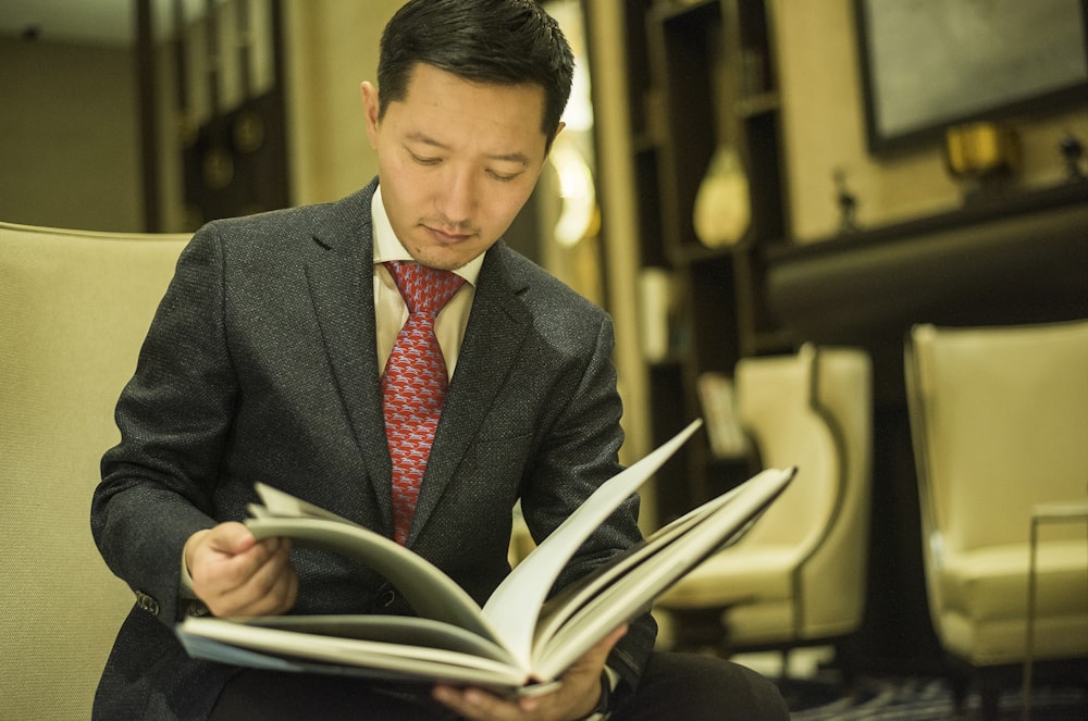 man in black suit reading book