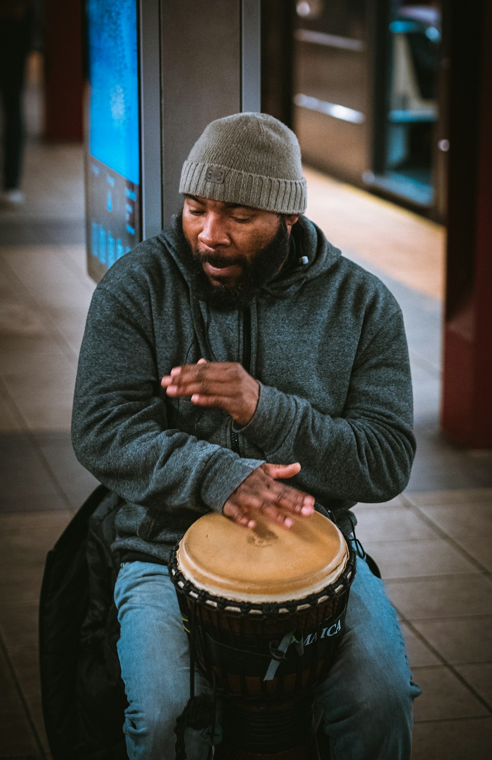 man in black knit cap and black jacket playing drum