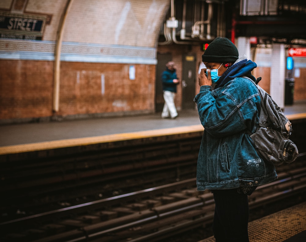 donna in giacca nera e pantaloni neri in piedi sulla rotaia del treno durante il giorno