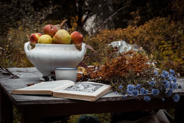 A rustic wooden table set with seasonal vegetables and a cozy cookbook open.