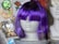 A mannequin head displays a vibrant purple wig with bangs covering the eyes. The background contains an assortment of items including a crown emblem, a floral pattern featuring a rose, and a cartoon character badge.