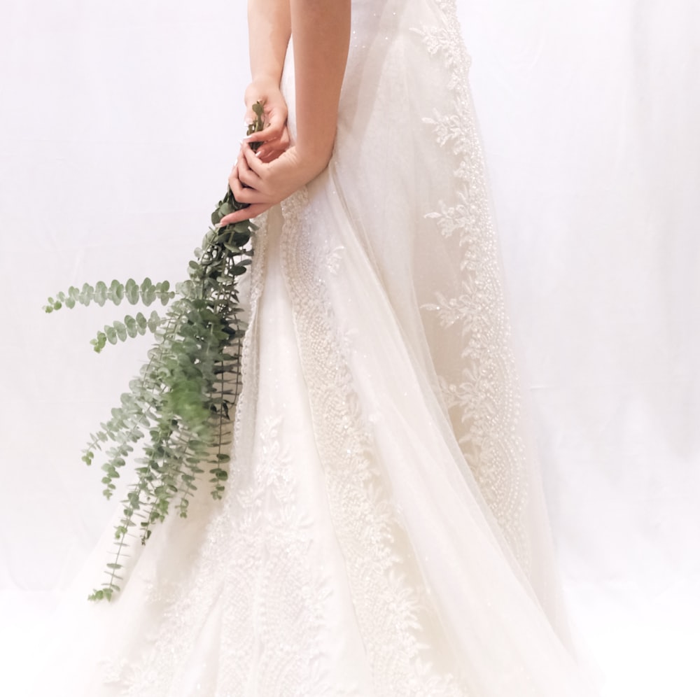 woman in white floral dress holding green plant