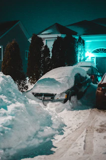 red car on snow covered road during night time